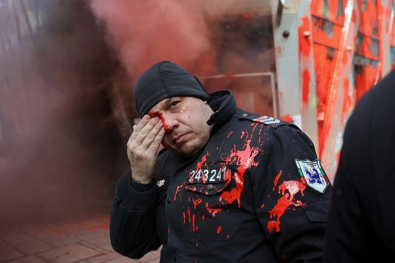 Bir polis memuru, hükümetin ülkeyi euro bölgesine alma planlarını iptal etmesini talep eden milliyetçi protestocularla çatışmalar sırasında gözünü tutuyor, 22 Şubat 2025